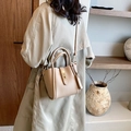 Beige Beuteltasche aus Leder mit Metallschloss, von Model im Trenchcoat getragen - Khaki