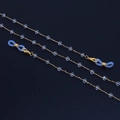 Catena per occhiali dorata con perle di cristallo trasparente su sfondo nero opaco - Oro