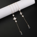 Gold metal eyewear chain with white clover charms and pearls on a black background - Gold Pearl Clover Style