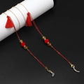 Detail of red tassel glasses chain with golden links and beads on black background - Red