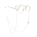 Close-up of gold round glasses frame with a silver chain and white floral pendant - White