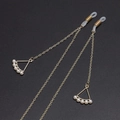 Golden metal eyewear chain with white pearls and hollow triangle pendant on dark background - Gold