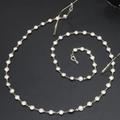 Elegante catenella per occhiali dorata con perle bianche su sfondo grigio scuro - Catena di Perle Dorate (GL424)