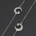 Silver chain eyeglasses strap featuring rhinestone star and moon pendants on black surface - Default