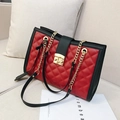 Quilted crossbody bag in red and black leather with golden chain strap on a sofa - Red