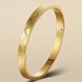 Dettaglio macro di bracciale in acciaio inossidabile dorato con trama a onde - Stile Onde Incise / Oro
