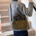 Olive green suede Boston bag with matte finish shown on shoulder in lifestyle setting - Green
