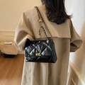 Elegant black quilted leather chain bag with golden ball adjuster on a model - Black