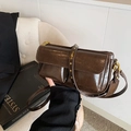 Donkerbruine crossbodytas met gouden klinknagels PARIS riem op beige stoel - koffiekleur