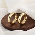 Orecchini a cerchio cavi placcati oro 18K lucido su un vassoio di legno scuro - Oro