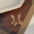 Detail of snake cuff earring with gold plating, white crystals, and green stone eyes - Gold