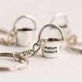 Macro shot of silver bucket keychain with Fuckit Bucket engraving and metallic texture - Bucket + Keychain / White Gold