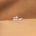 Silver infinity and cross ring with zircon accents on a textured brown surface - US Size 7 Adjustable / White Gold