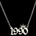 Detailopname van een zilveren ketting met jaartal 1990 en kroonvormig sieraad - Zilver (1990)