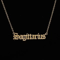 Macro shot of a gold Sagittarius necklace with gothic lettering on a black background - Sagittarius Gold