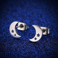 Dettaglio macro di orecchini a mezzaluna d'argento con stelle su sfondo glitter blu - Color Acciaio