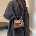 Classic brown leather Kelly style handbag with green woven strap worn by model - Brown