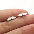 Detailed close-up of silver mustache-shaped stainless steel stud earrings on a finger - Mustache Style (679) / Steel
