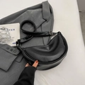 Sac demi-lune noir mat avec bandoulière réglable et détails dorés sur veste grise - Noir