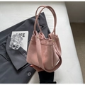 Rosa Wildleder-Eimertasche mit runden Griffen und goldenen Nieten in eleganter Kulisse - Rosa