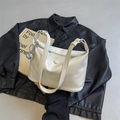 Detail of cream white patent leather handbag with wavy texture and silver ball charm - With Pendant / Off White