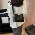 Bolso saco de cuero granulado negro con correa ancha de tela y detalles en metal dorado - Negro