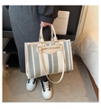 Detail of canvas tote bag with contrast stripes and leather trim on a person's side - Large / Blue