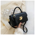 Schwarze Handtasche mit Krokoprägung und Goldverschluss vor Tweed-Hintergrund - Schwarz