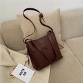 Borsa a secchiello in pelle marrone scuro con manici e tracolla su divano beige - Fucsia