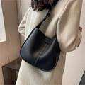 Vista laterale di una borsa a secchiello in pelle nera indossata da una modella - Nero