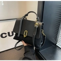 Dettaglio borsa a mano in pelle nera con chiusura ovale dorata e contrasto di texture - Nero