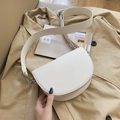 Bolso tipo silla de montar en cuero beige con correa ancha sobre una gabardina - Blanco