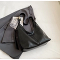 Black pebbled leather tote bag with gold metal buckle detail in a stylish urban setting - Black
