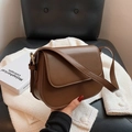 Bruine lederen crossbodytas met klep en verstelbare riem op minimalistische achtergrond - koffiekleur