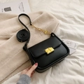 Minimalist black leather crossbody bag with golden buckle and chain on white fabric - Black