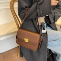Klassieke bruine crossbodytas met gouden gesp gedragen bij een casual outfit - Bruin