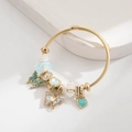 Goldenes Wickelarmband mit blauem Schmetterlingsanhänger und Herzanhänger auf Weiß - Blau