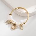 Goldenes Perlenarmband mit Kristallschmetterlingen und Herzanhängern auf Weiß - Weiß