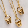 Three gold bucket pendant necklaces with Fuckit Bucket engraving on marble surface - Bucket + Necklace / Gold