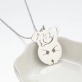 Collar con colgante de cerdo hueco en plata pulida sobre un plato cerámico decorativo - Color Acero