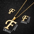 Golden vintage F-letter pendant necklace and stud earrings set on black glitter background - Gold F
