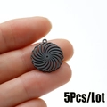 Dettaglio di 5 ciondoli a fiore a spirale nera in acciaio inossidabile tenuti in mano - Stile disco a spirale (537) / Nero