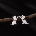 Sleek stainless steel waving cat stud earrings with hollow heart detail on black background - Steel
