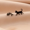 Vista macro di orecchini asimmetrici a forma di gatto e lisca in nero opaco su seta - Nero