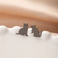 Dettaglio di orecchini asimmetrici a lobo con gatto e topo in acciaio su piatto ceramica - Nero