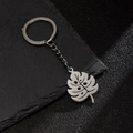 Detail shot of hollowed-out monstera leaf keychain on black stone textured background - Hollow Monstera Leaf (199)