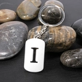 Polished stainless steel keychain with cutout letter I on a black textured stone surface - Letter I