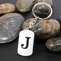 Polished stainless steel keychain with hollow letter J pendant on stone background - Letter J