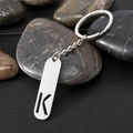 Polished stainless steel rectangle keychain with hollow letter K on dark pebbles - Letter K