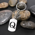 Polished stainless steel keychain with cut-out letter Q pendant on stone background - Letter Q